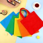 A stack of 25 Aneco non-woven party favor bags in assorted rainbow colors: red, orange, yellow, green, and blue.