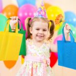 A stack of 25 Aneco non-woven party favor bags in assorted rainbow colors: red, orange, yellow, green, and blue.